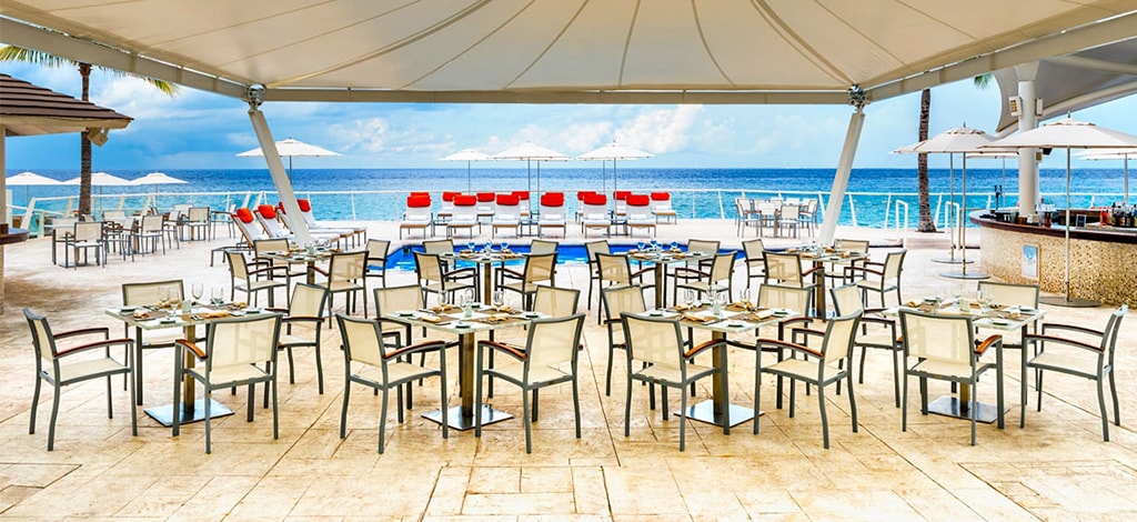 Tables at Flamingos sit under a large sun shade on the pool deck. It's a favorite for quick lunch bites and evening barbecues.