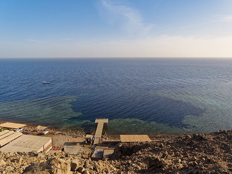 The Dahab Blue Hole sits on the inner edge of a deep wall. The Dahab Blue Hole sits on the inner edge of a deep wall.