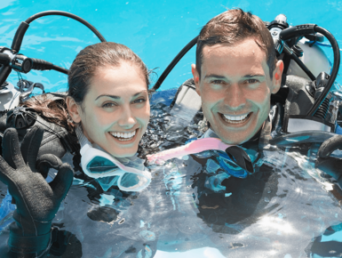 Smiling couple on scuba training in swimming pool showing OK gesture on a sunny day